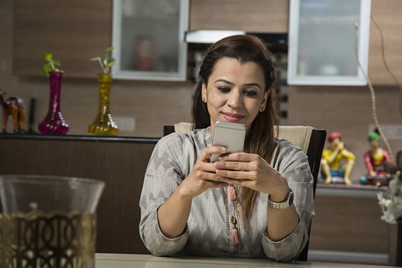 A young woman smiles while looking at her smartphone