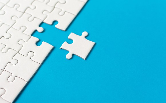 White jigsaw puzzle with an edge piece being removed