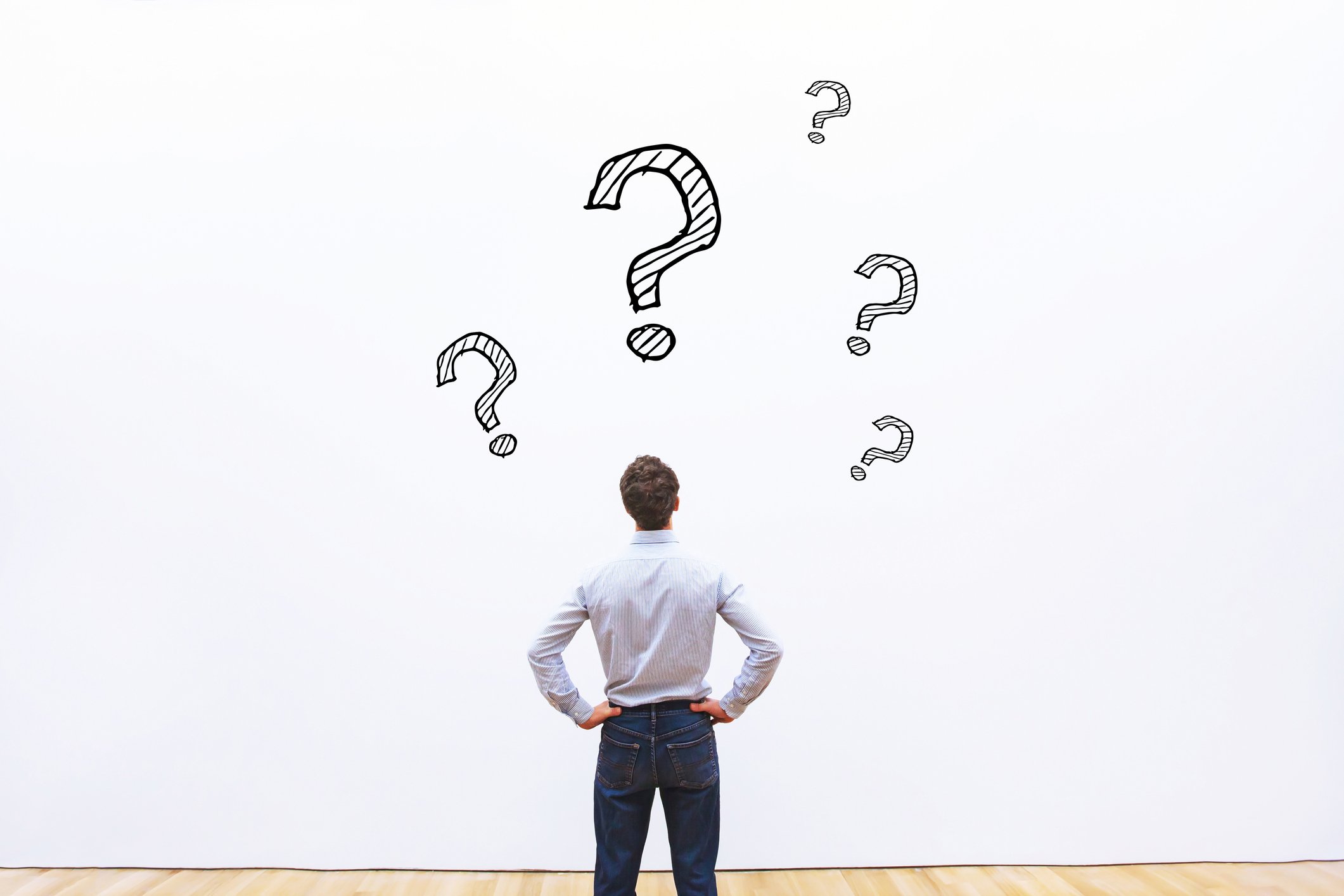 A man staring at several question marks on a wall