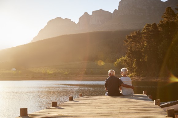 An older man and woman sitting on the edge of a dock