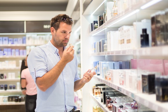 A man smelling perfume in a store.
