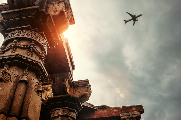 An airplane flying above a temple.