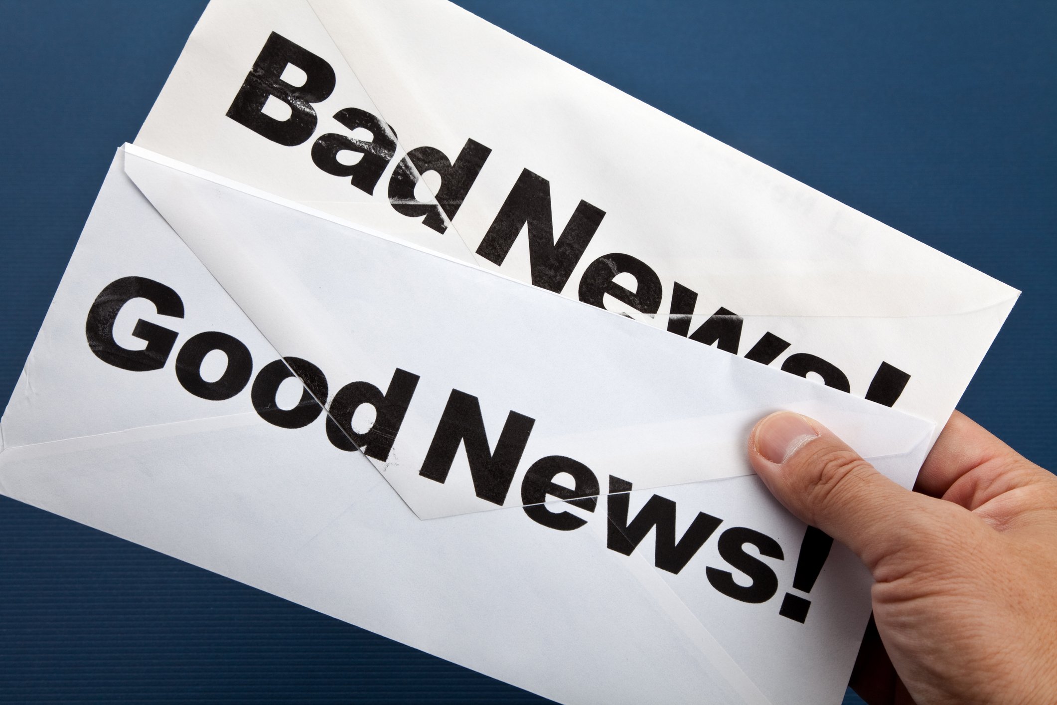 Hand holding envelopes with "good news" and "bad news" printed on them