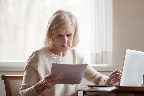 Older woman reviewing her finances while seated at her desk.