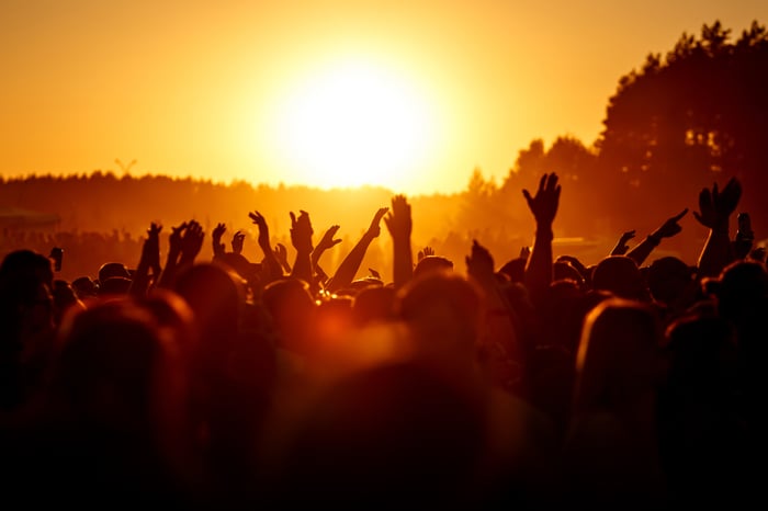 People at an outdoor concert with their hands in the air