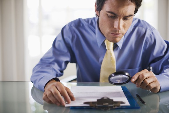 A businessman reading a document with a magnifying glass.
