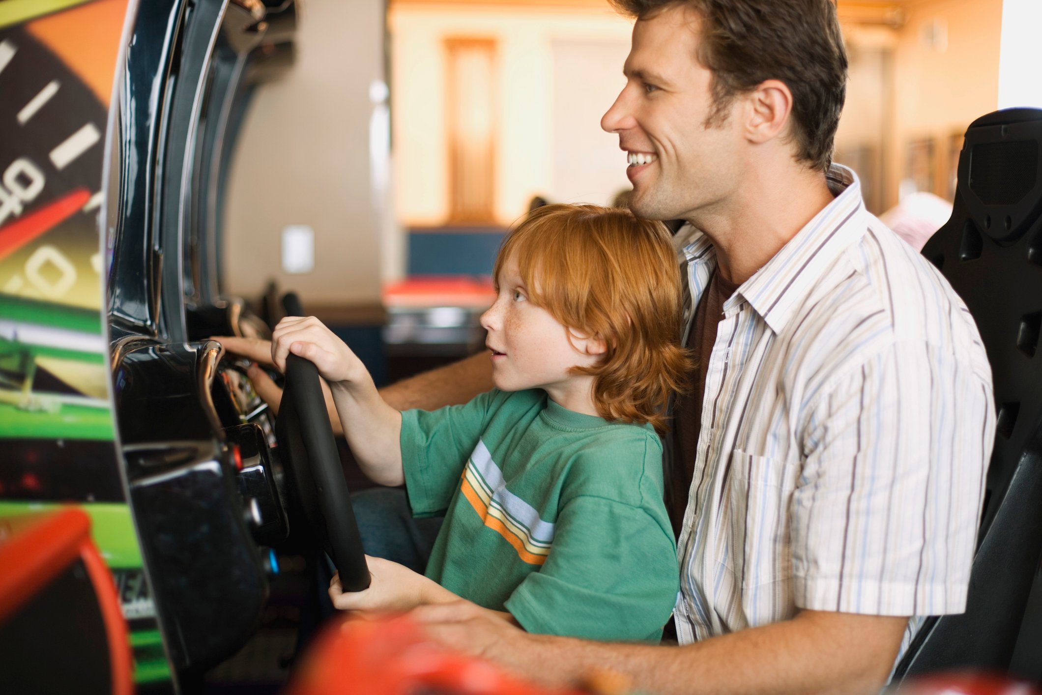 A father and son playing arcade games together.