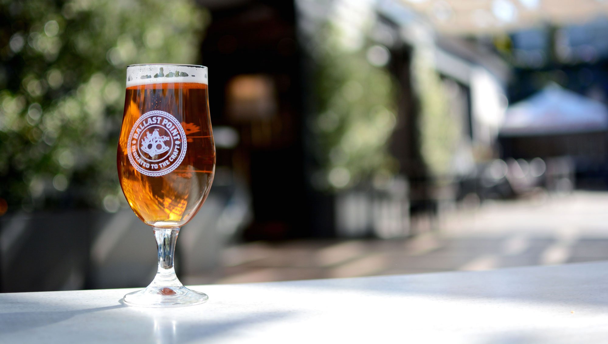 A glass of Ballast Point beer sitting on a table.