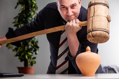 Man holding wooden mallet over pottery urn