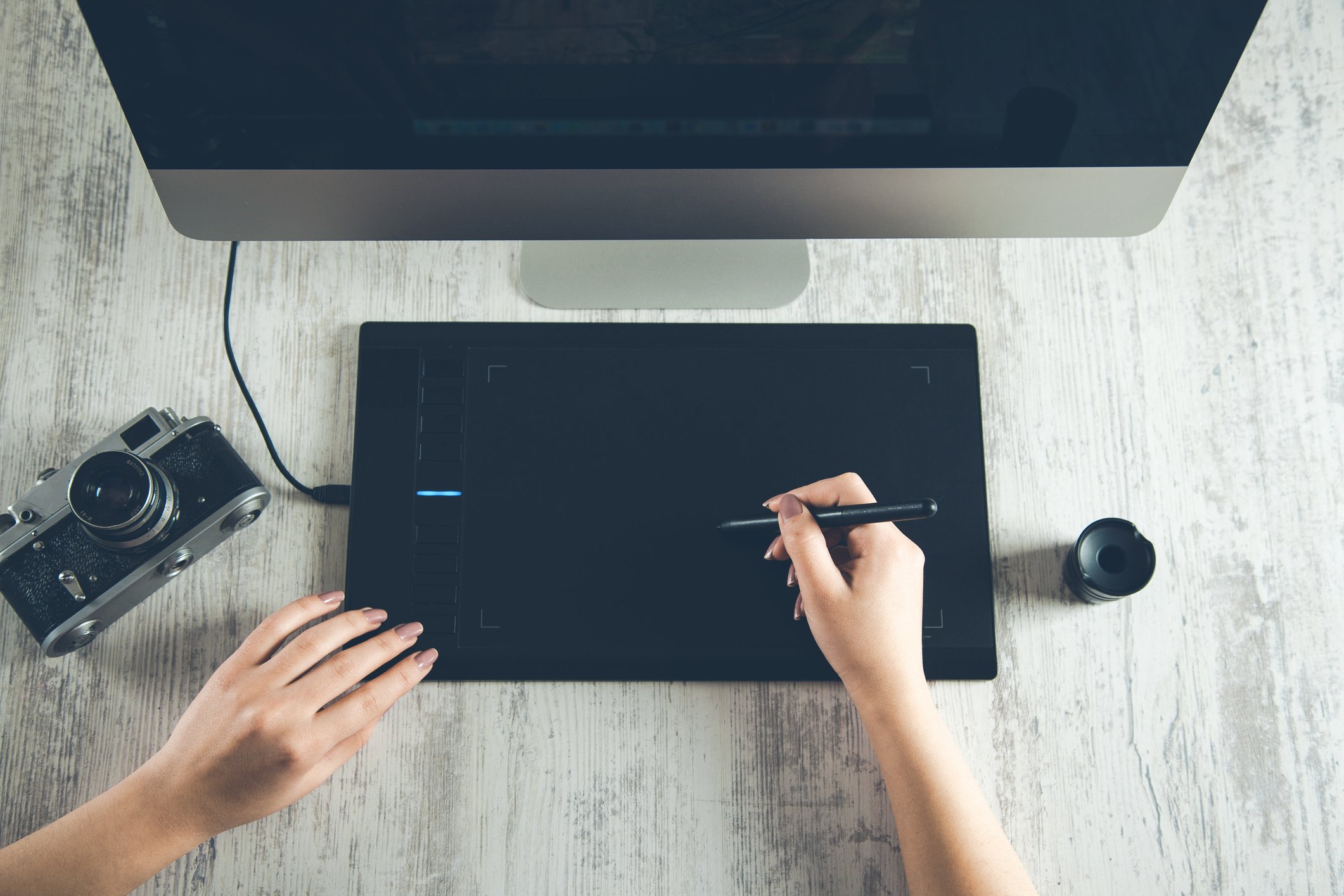 A woman's hand poised over a drawing tablet