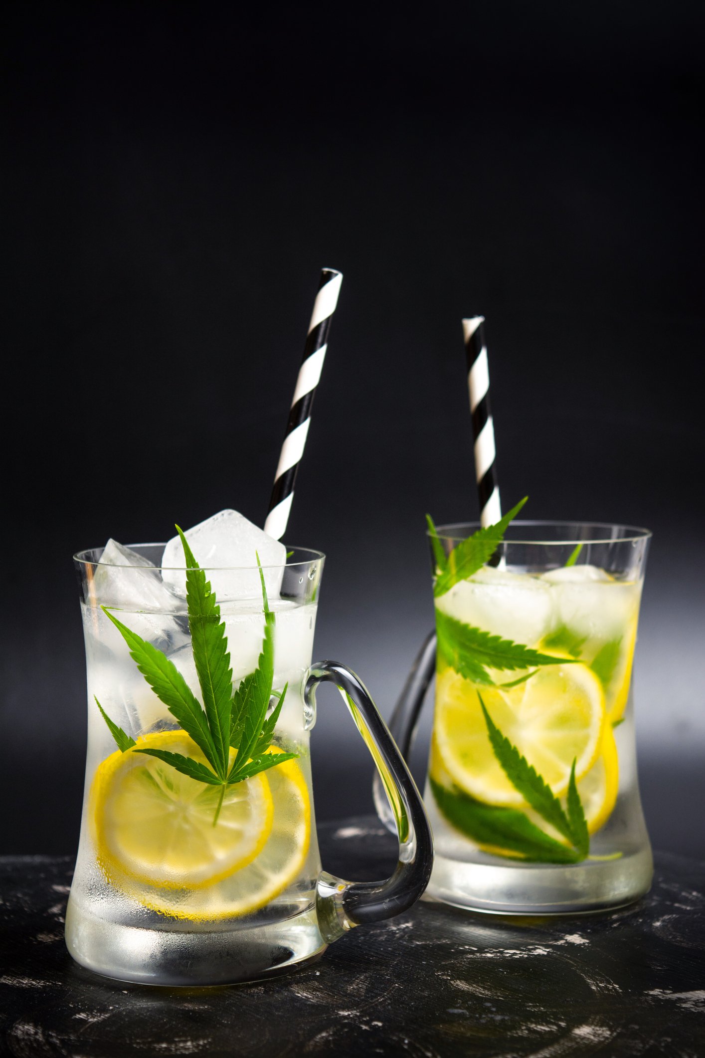 Two drinks containing lemons and marijuana leaves.