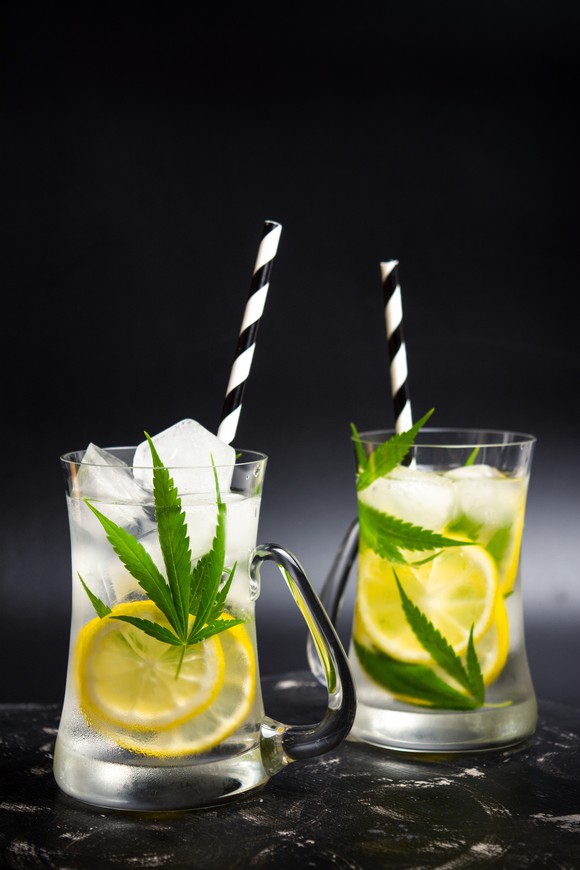 Two drinks containing lemons and marijuana leaves.