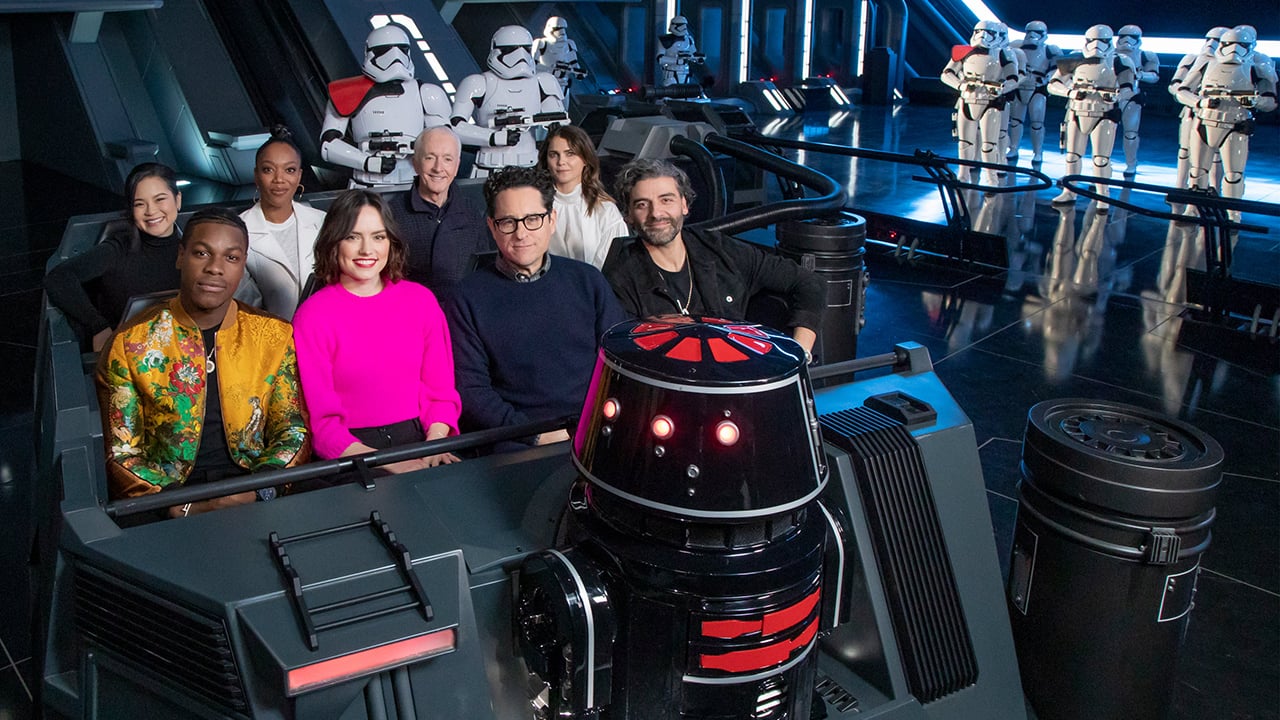 The cast of Star Wars: The Rise of Skywalker enjoying a ride on Rise of the Resistance with Stormtroopers in the background..