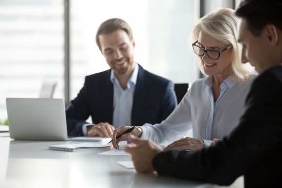 Three people in business attire working at a conference table.