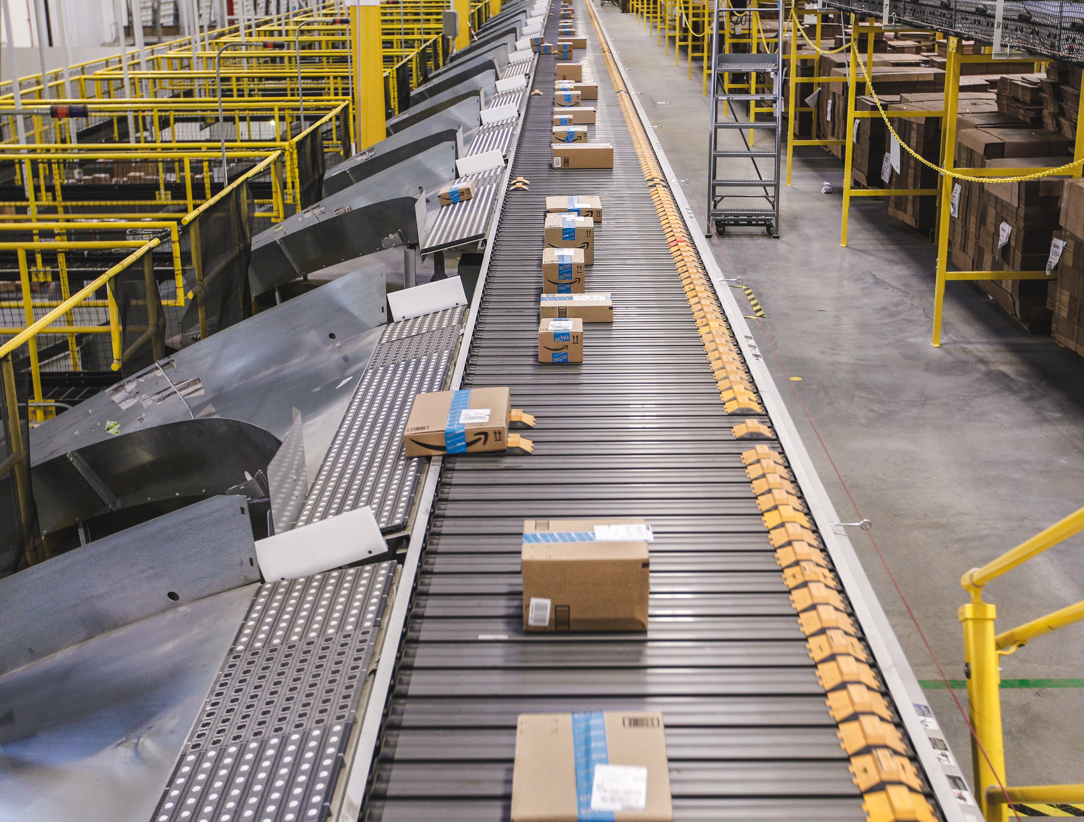 Cardboard boxes coming down a conveyor belt in an Amazon fulfillment center.