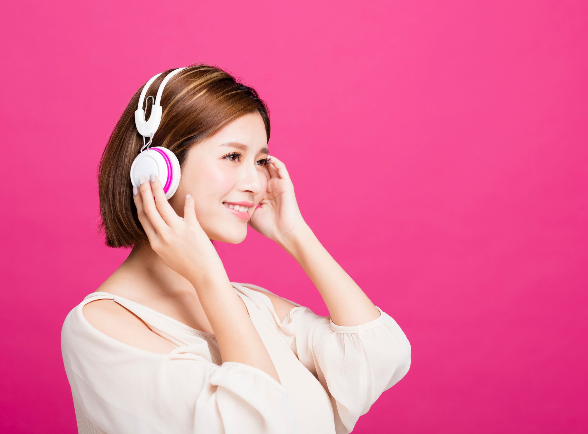 A young woman listens to music on her headphones.