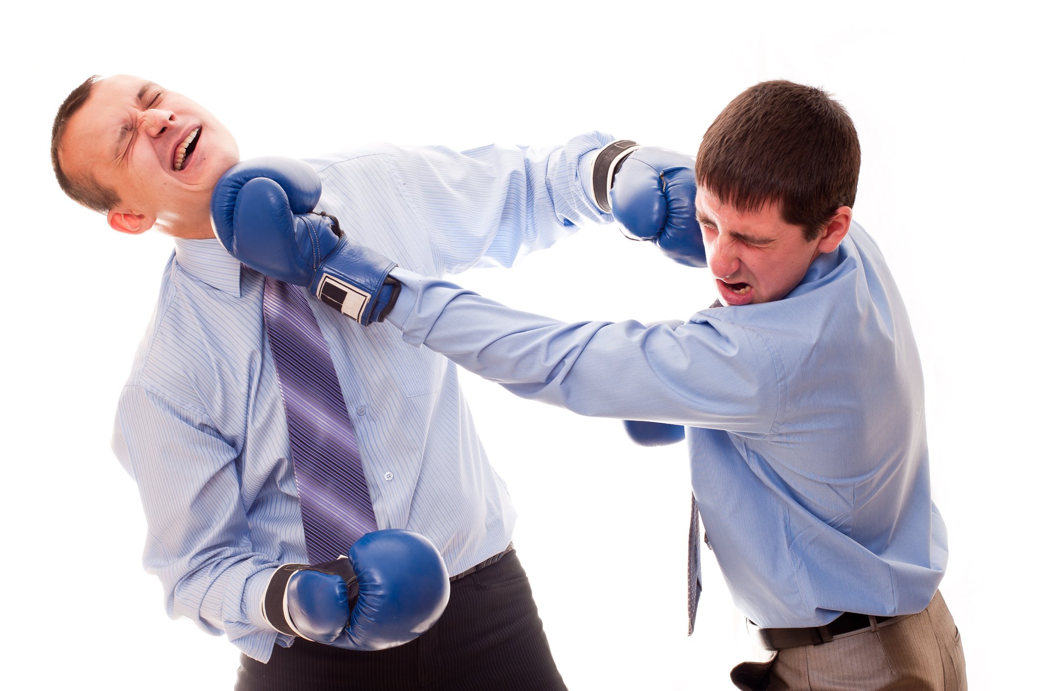 Two men in business attire and boxing gloves punching each other.
