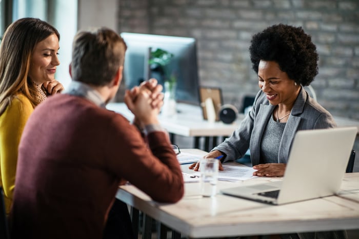 A couple sitting across a desk from a woman