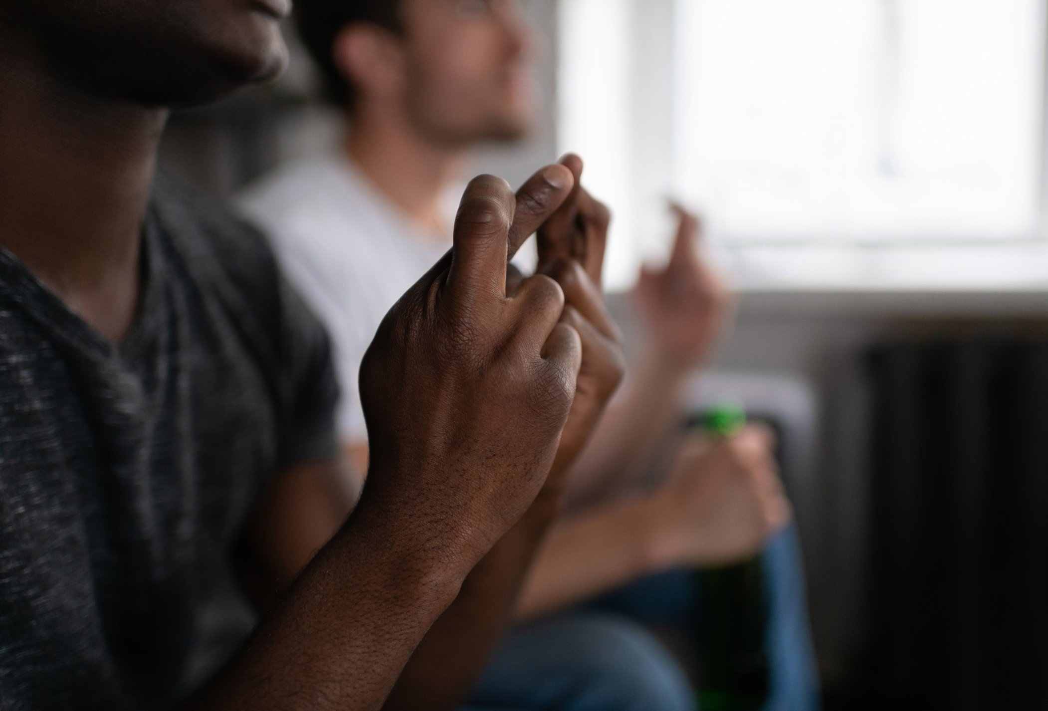 Guy crossing fingers with blurred friend in the background