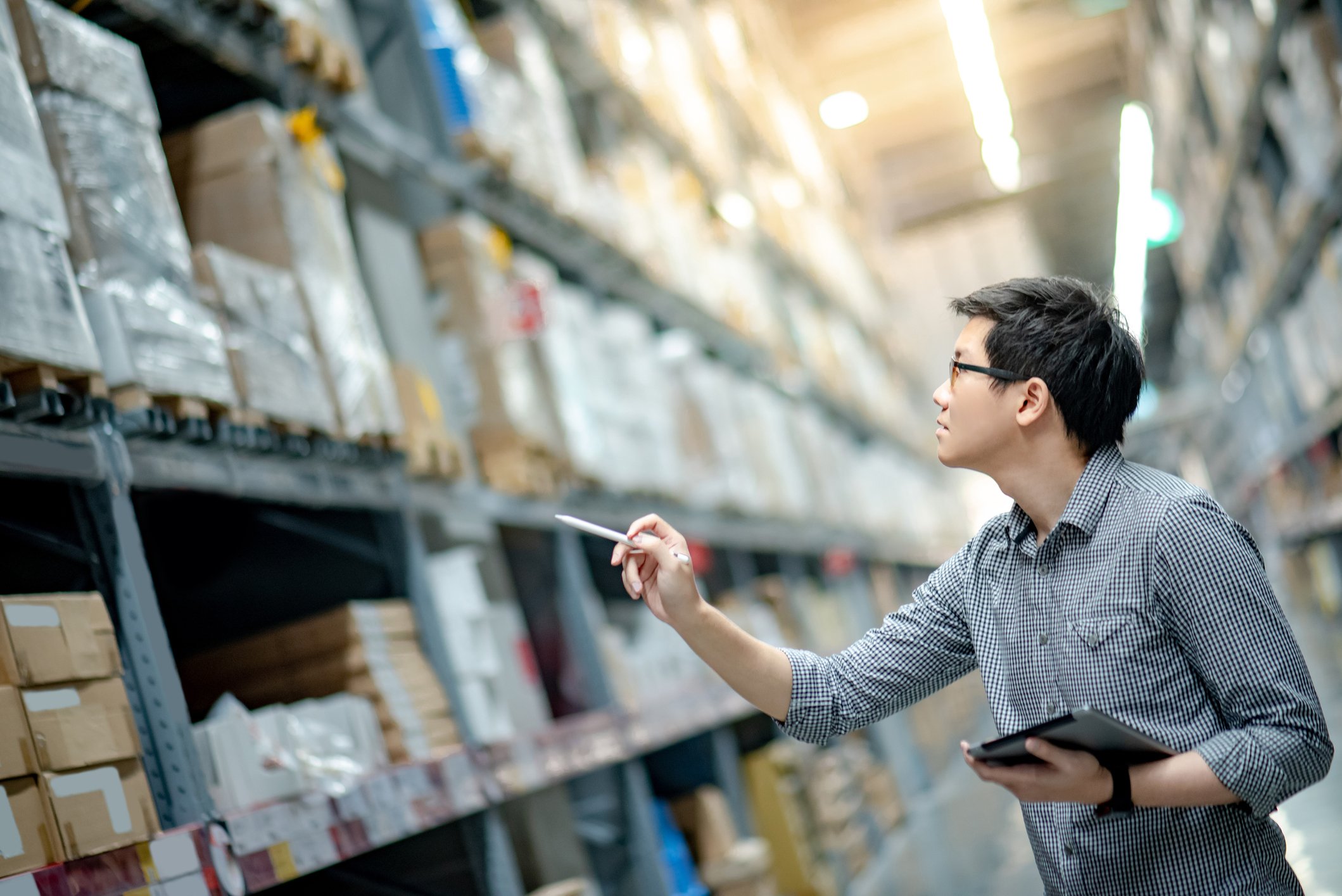 Man counting inventory between shelves in a warehouse