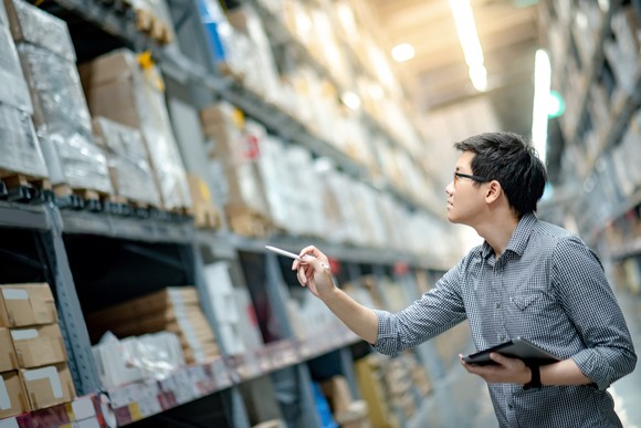 Man counting inventory between shelves in a warehouse