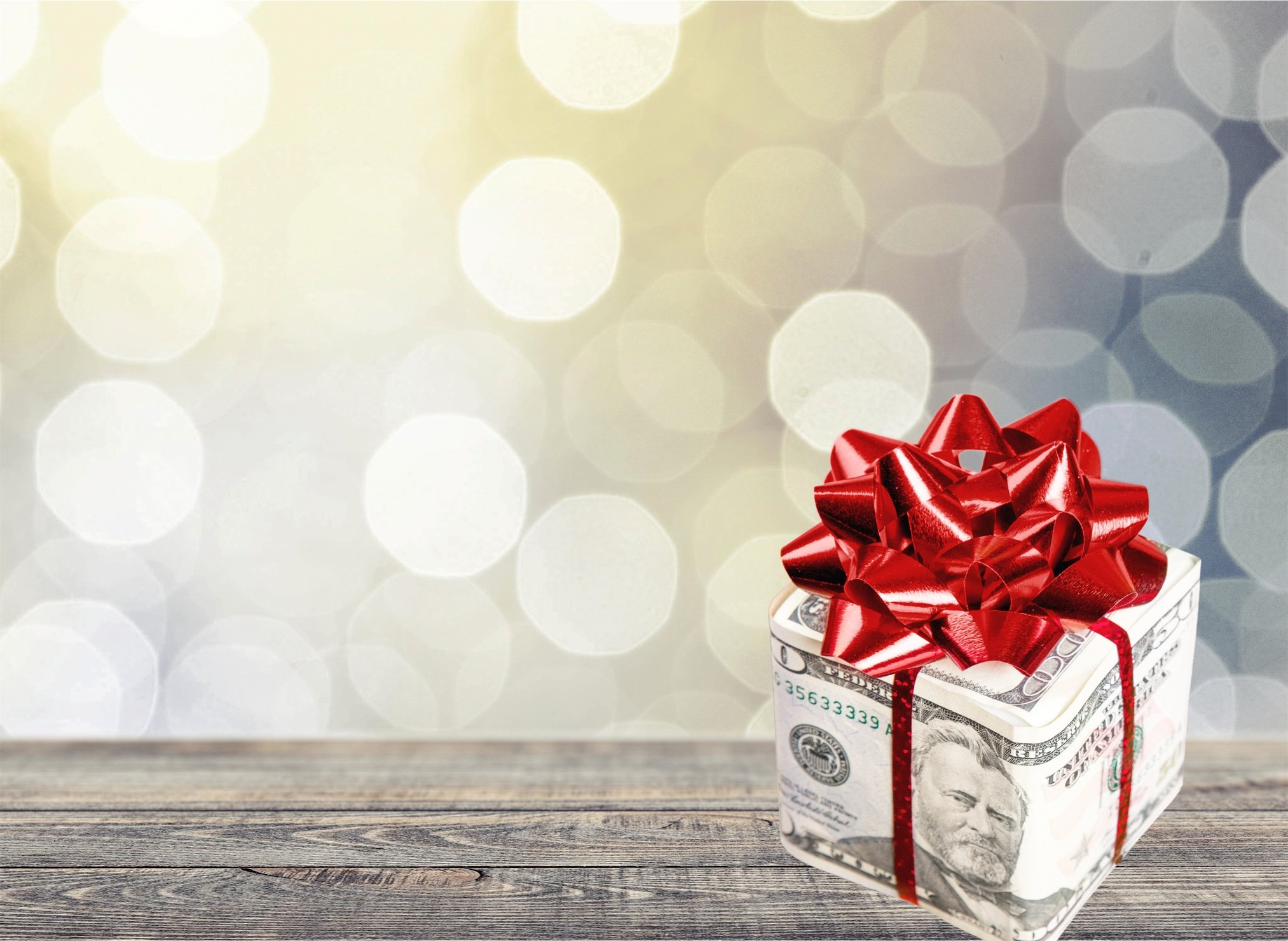 A package is wrapped in a fifty dollar bill and a red bow.