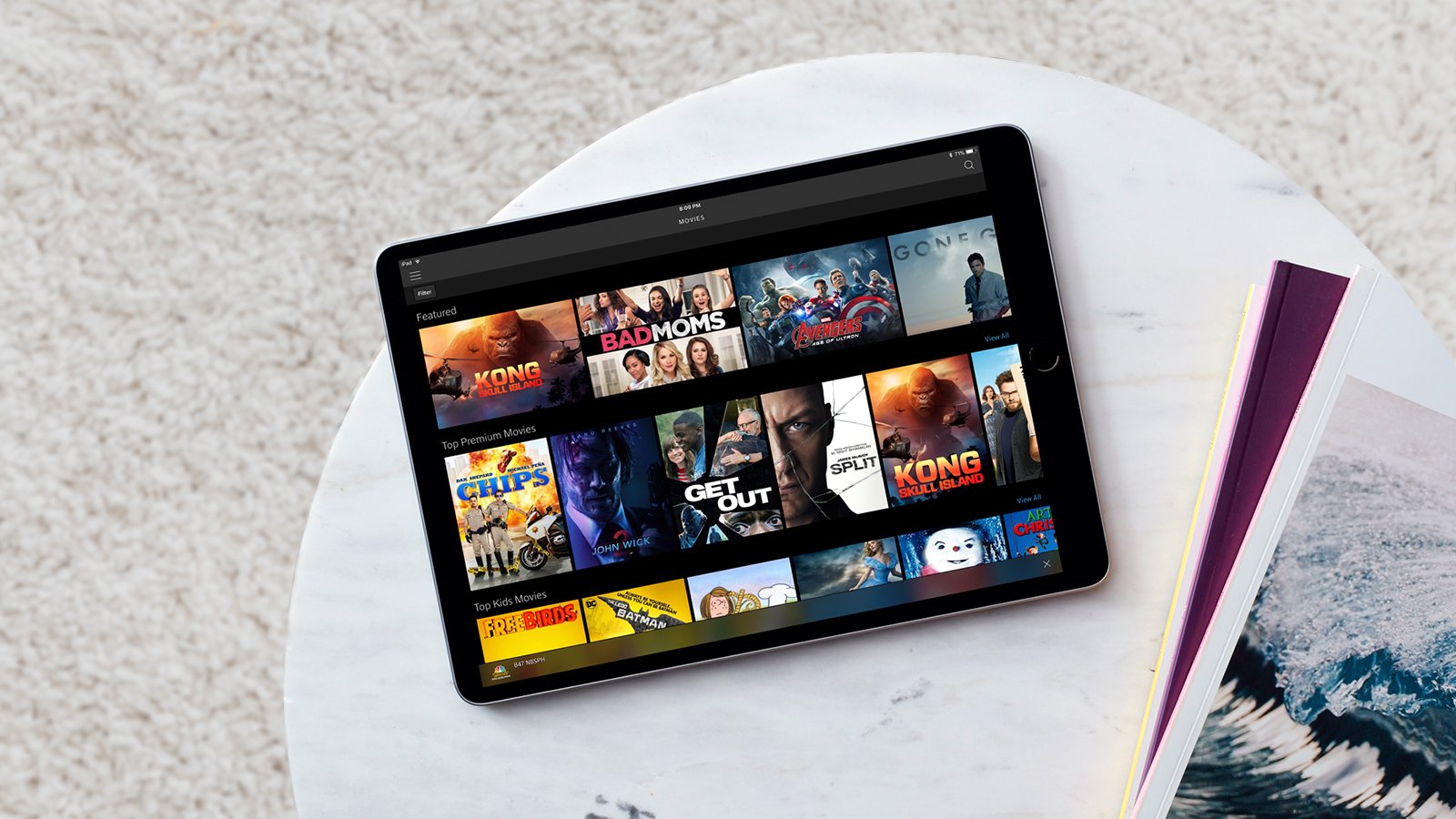 A tablet computer laying on a table with the Comcast Xfinity streaming app displayed on the screen.