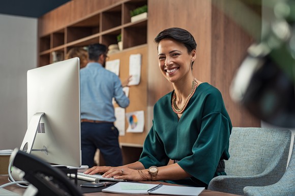 A woman smiling behind her desk
