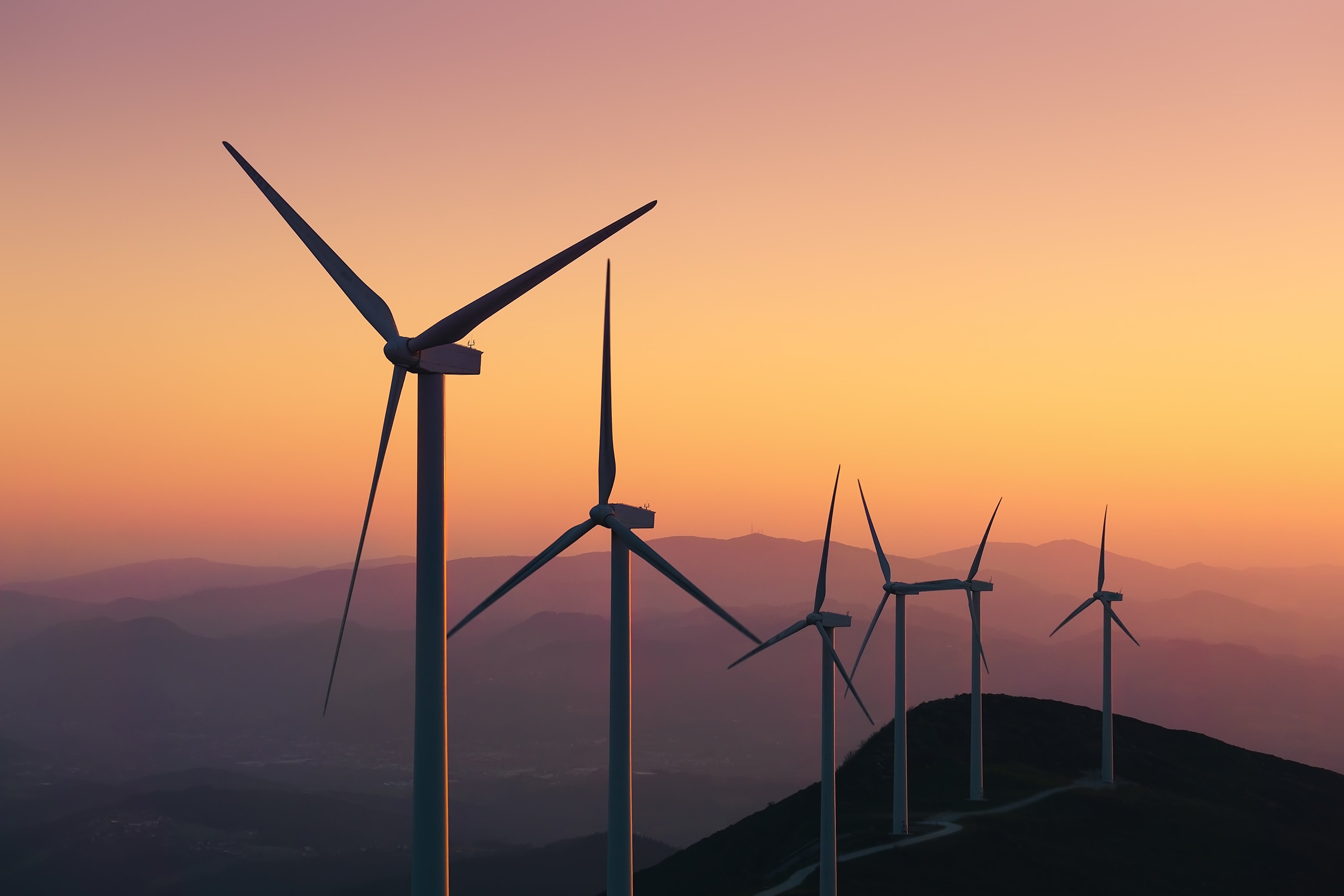 Wind turbines on the top of a hill at dusk. 