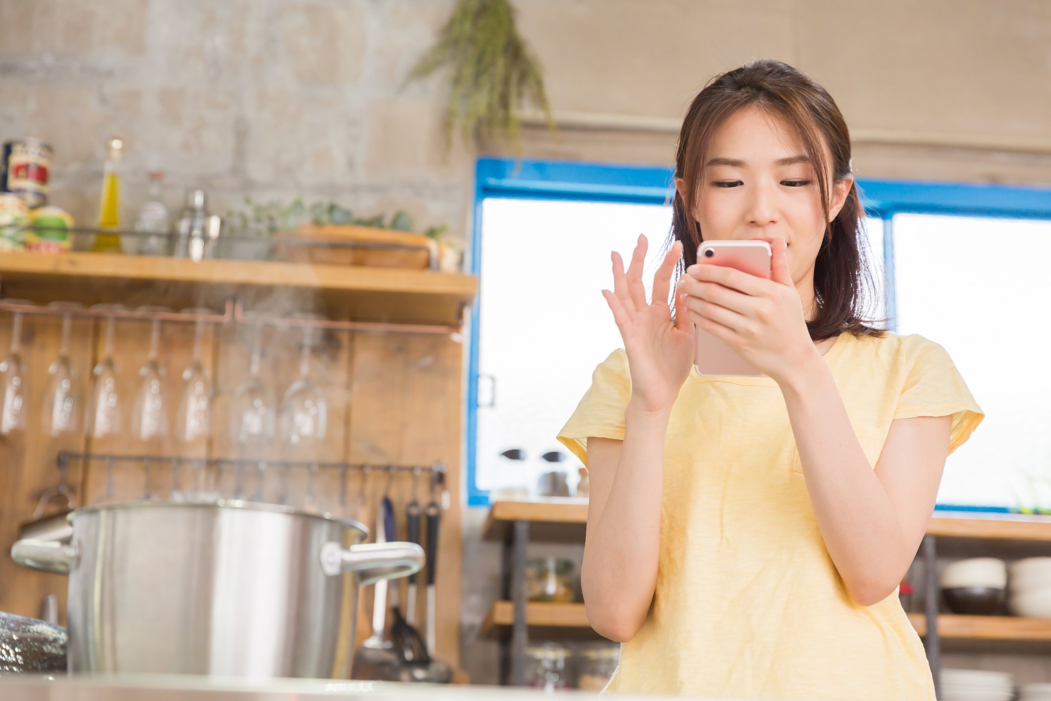 A young woman uses a smartphone in a kitchen.