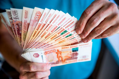 Man fanning a stack of Russian ruble banknotes