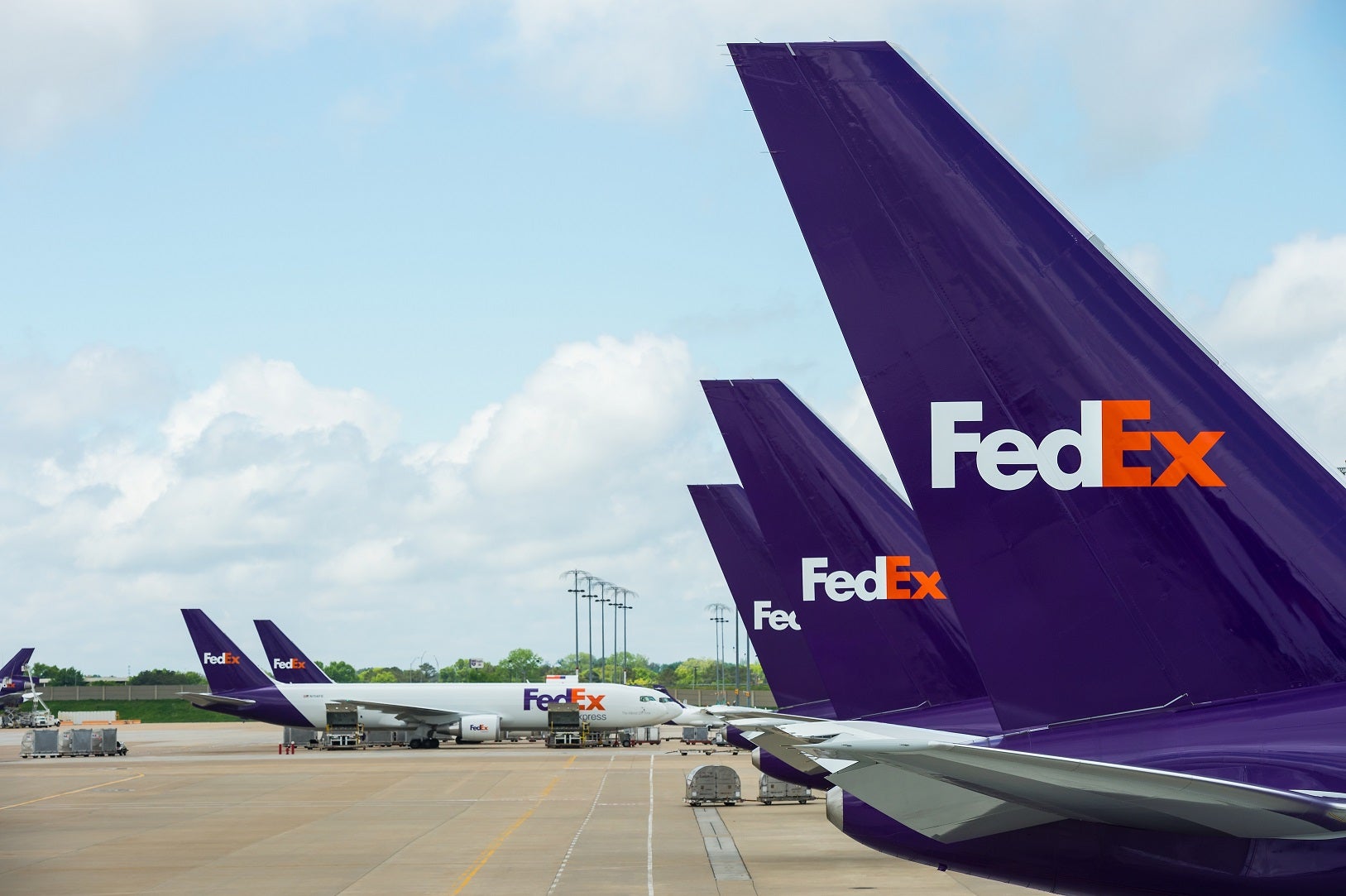 Several planes at an airport with the FedEx logo on their tails.