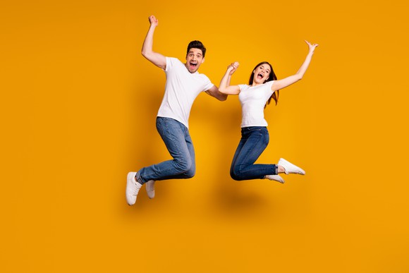 A man and a woman smiling and jumping in the air.
