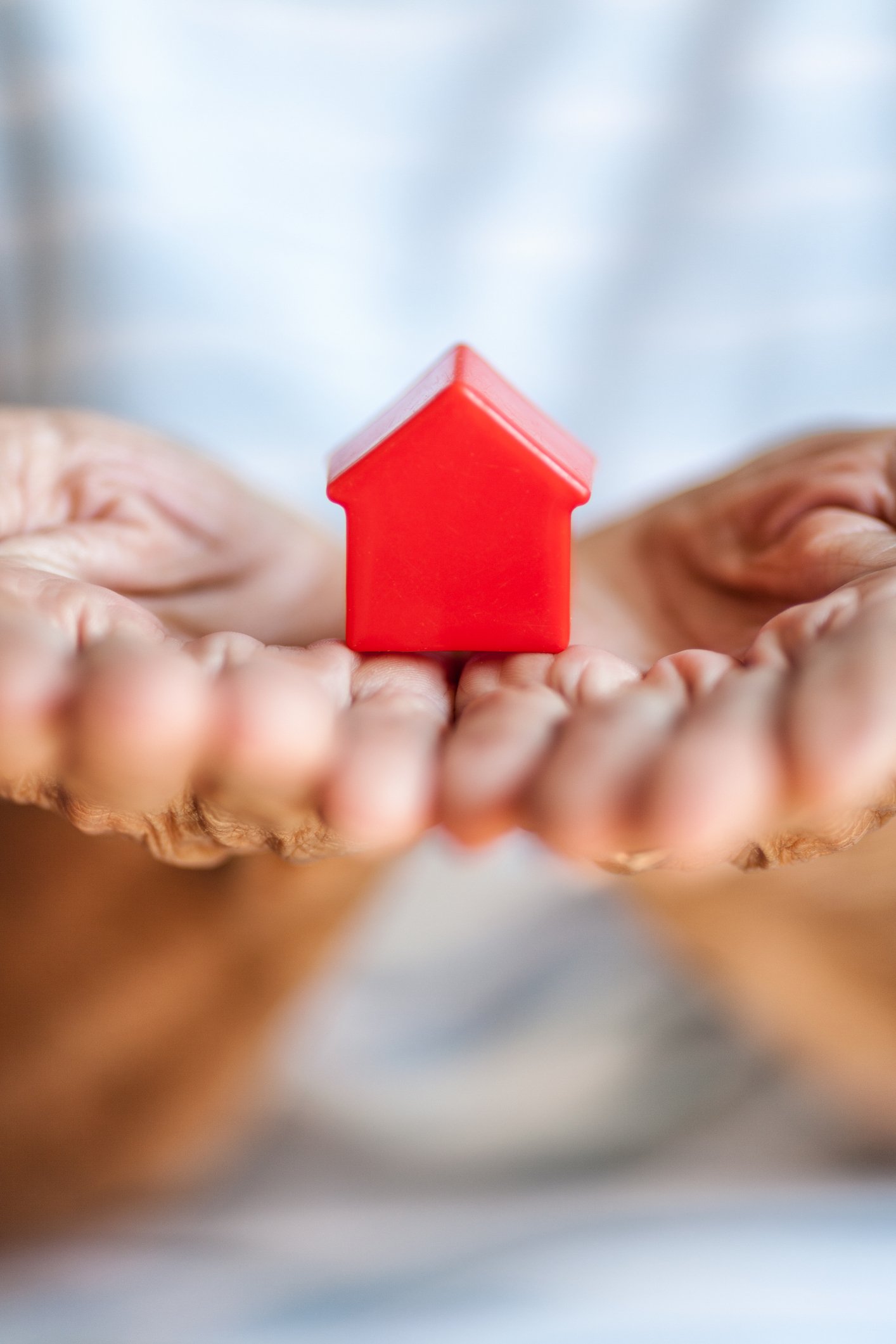 person holding small red house in their hands