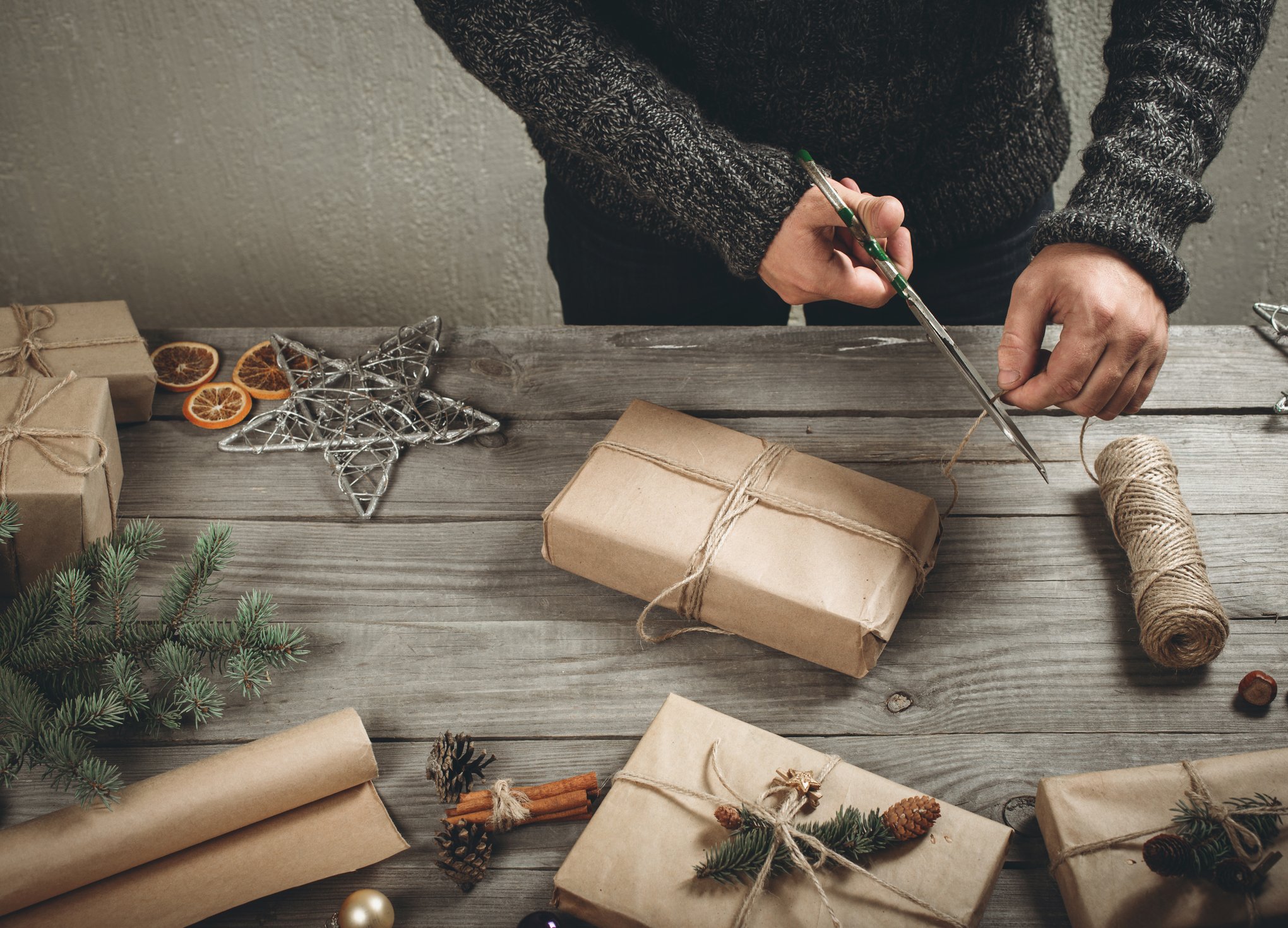 Male hands wrapping Christmas gift on wooden table
