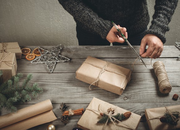 Male hands wrapping Christmas gift on wooden table
