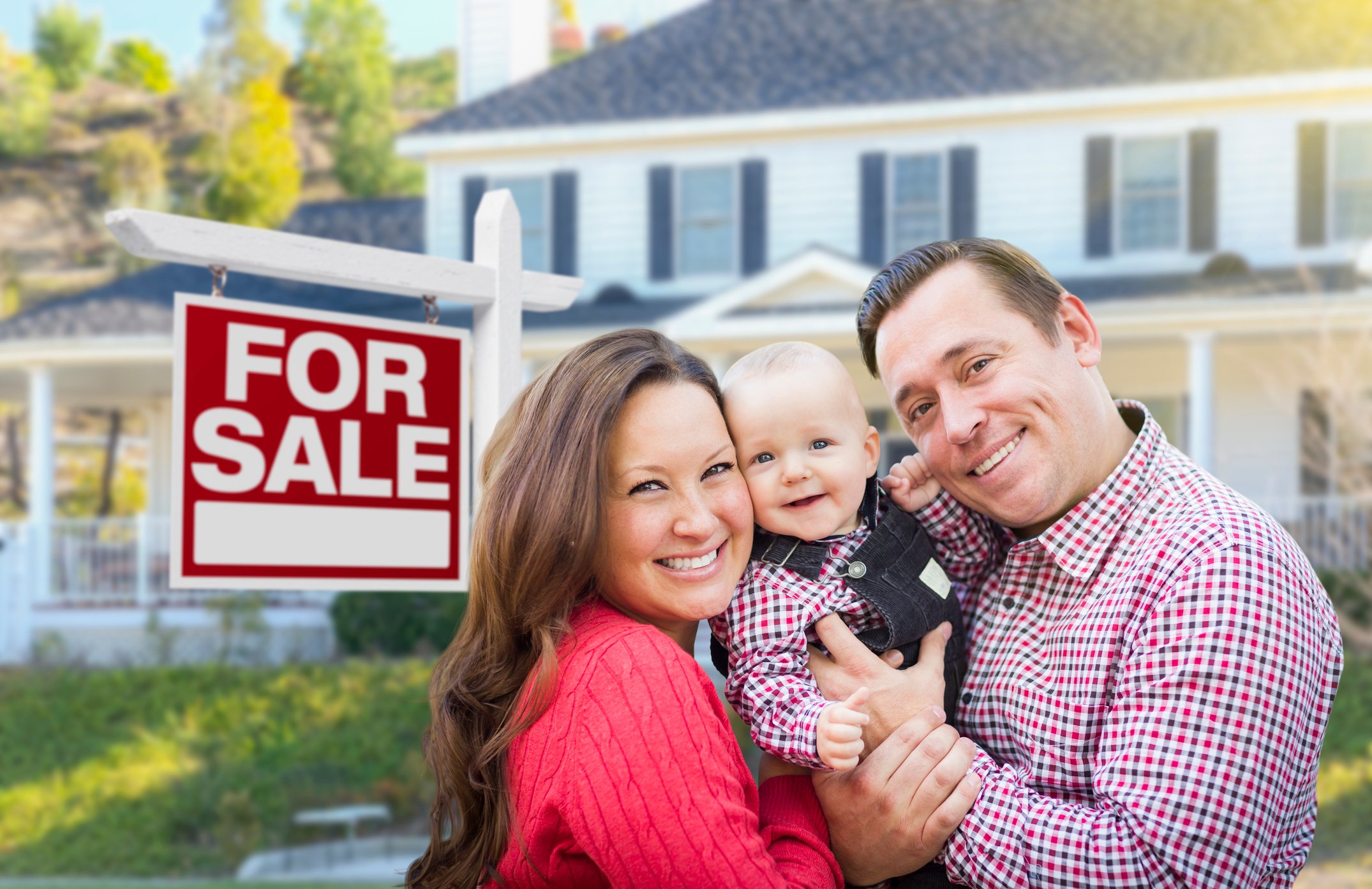 Family in front of for sale sign