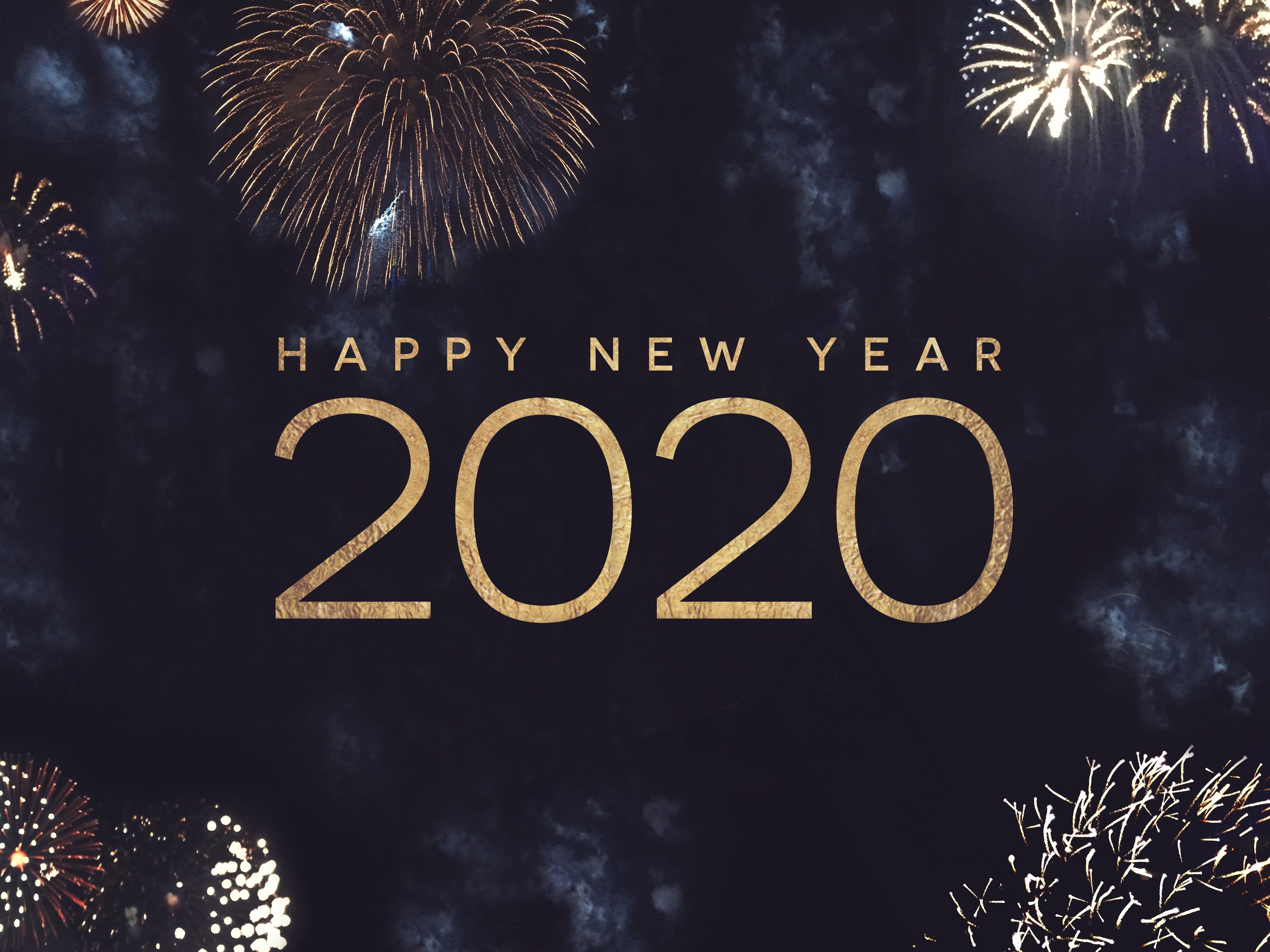The words happy new year 2020 in gold against a dark blue background with fireworks