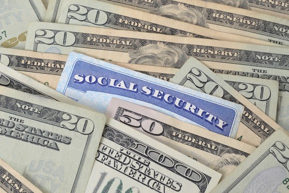 A Social Security card wedged between a pile of cash bills.