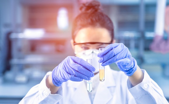 Female scientist in a lab holding up two test tubes