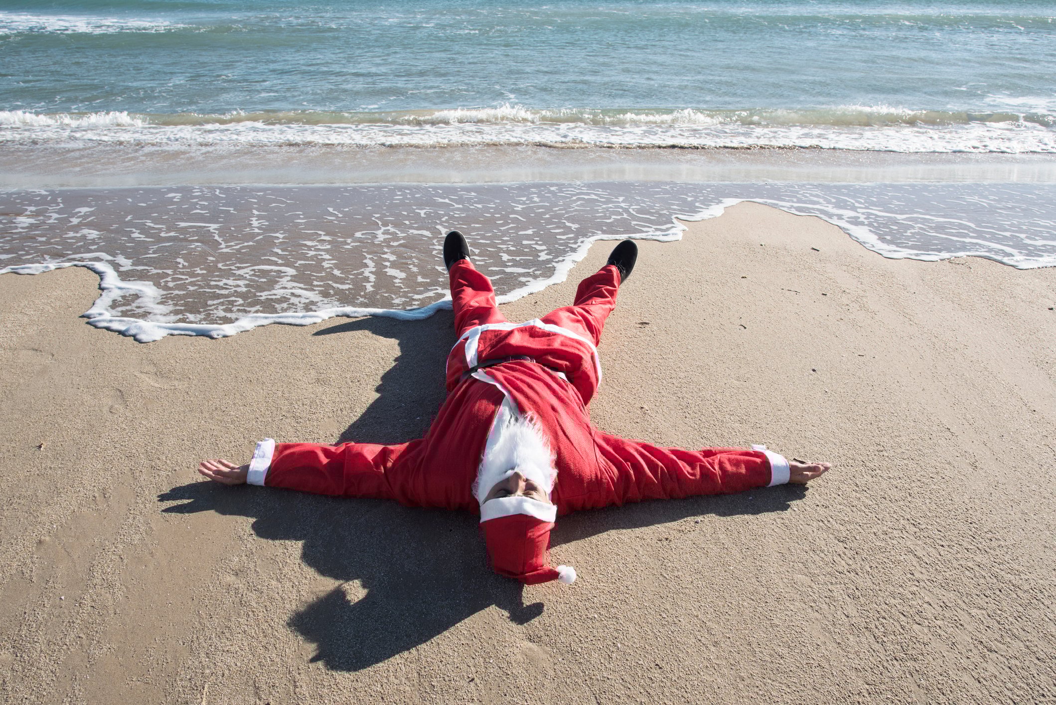 Santa Claus lying on a beach