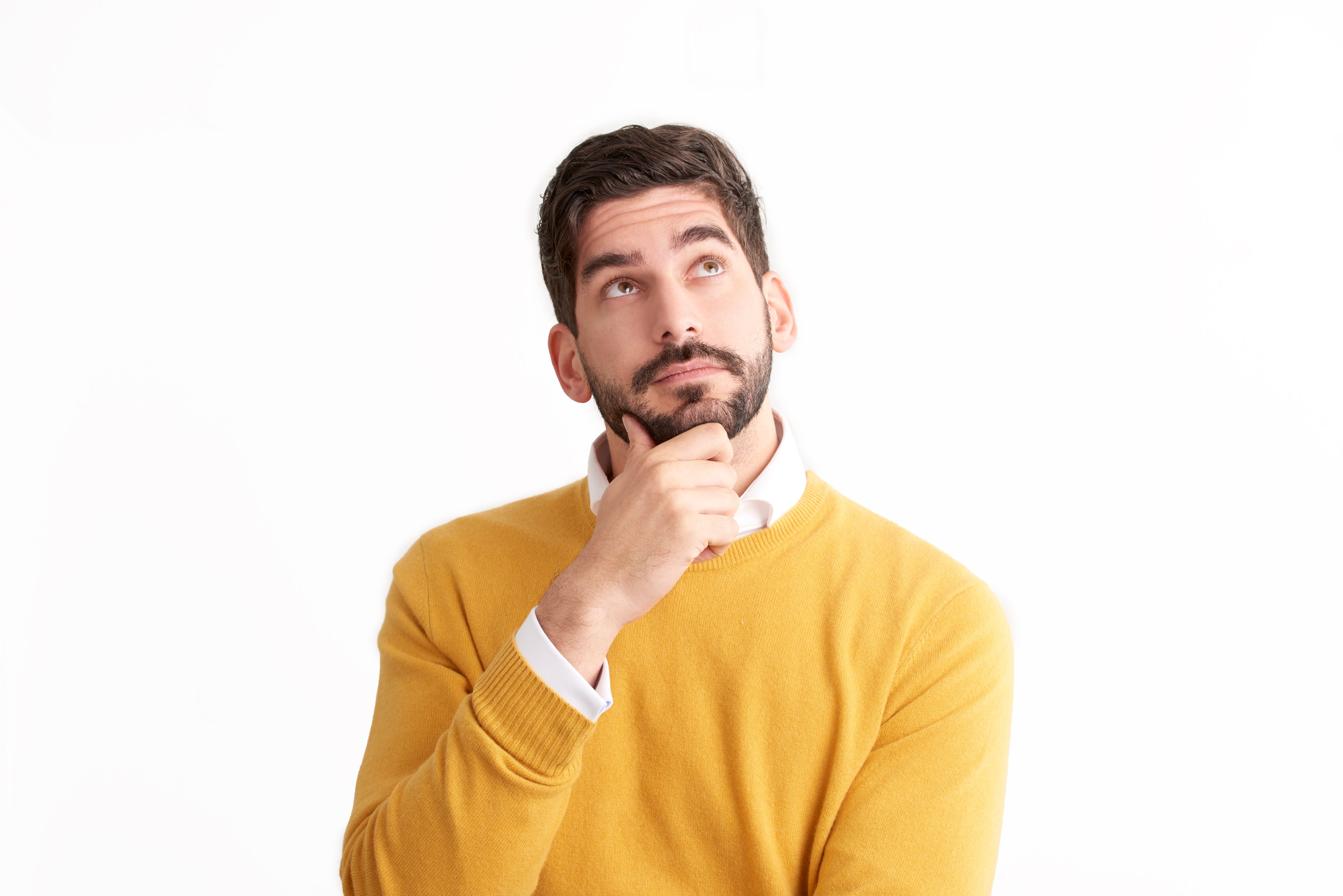 Man in yellow sweater with hand on chin, looking up and thinking