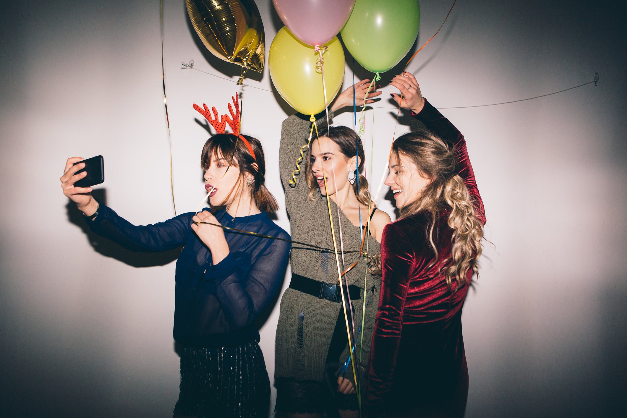 Three young women take a selfie with balloons.