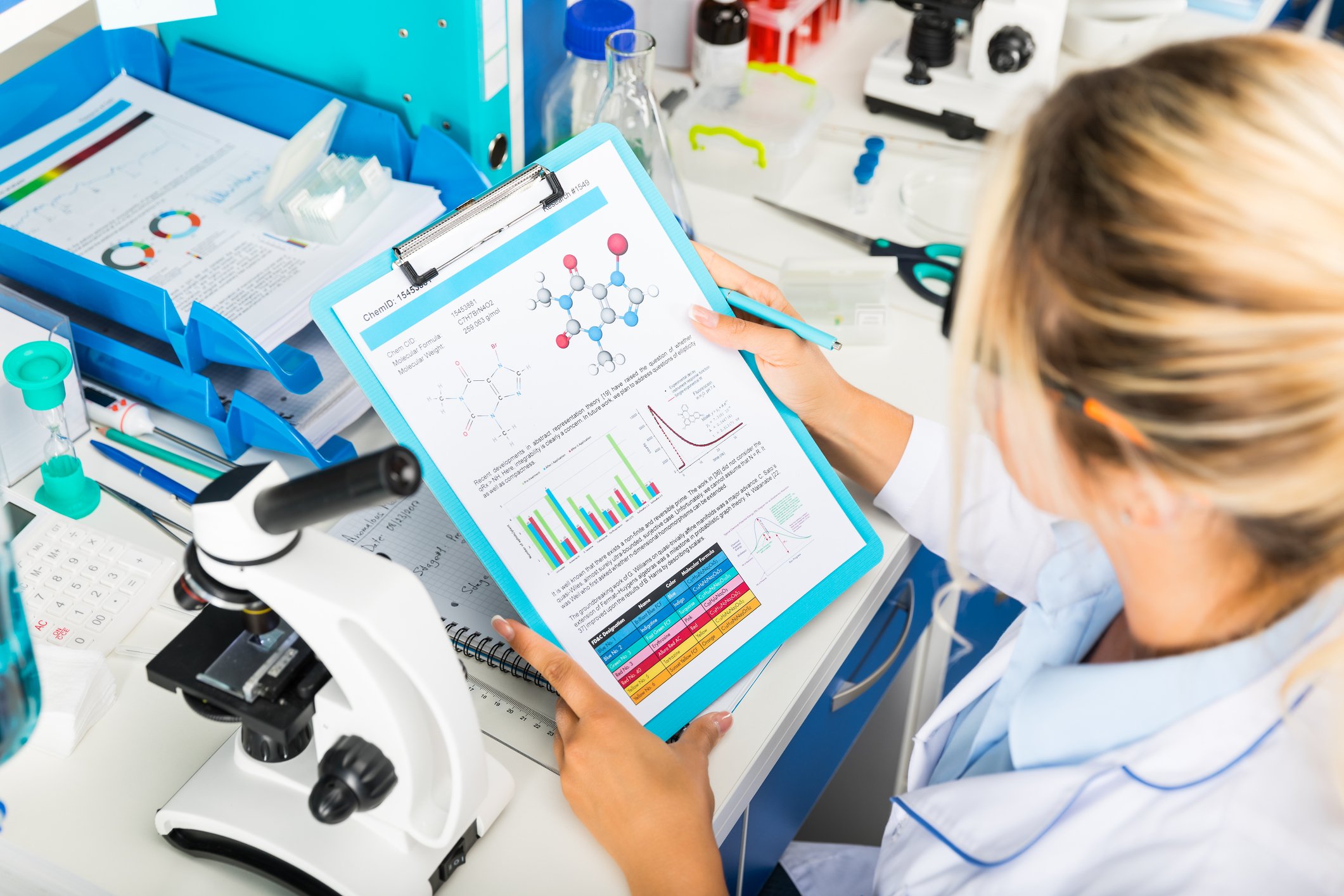 Female scientist reading a chart on a clipboard.