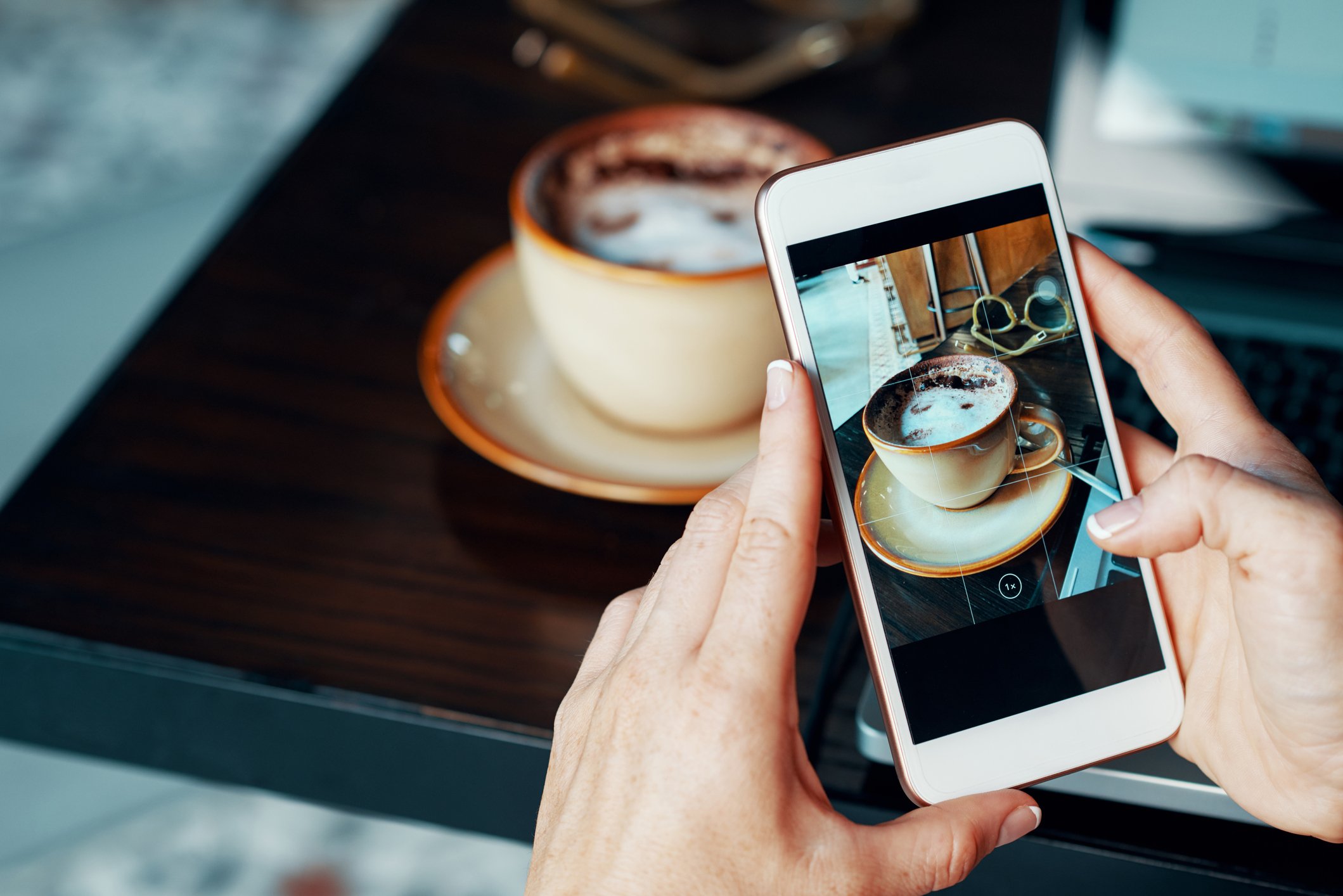 A person takes a picture of coffee with a smartphone.