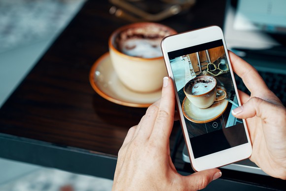 A person takes a picture of coffee with a smartphone.