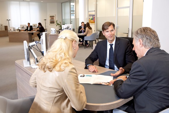 A couple consulting with a banker inside a bank branch.