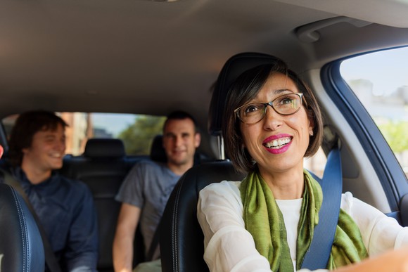 An Uber driver transporting two passengers in her car. 