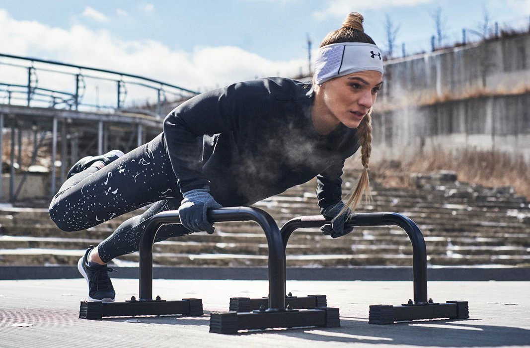 A woman in UA apparel does push ups.