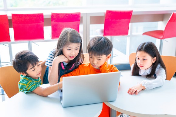 Four young children looking at a computer.
